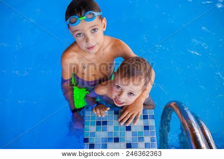 Funny Boy And His Cute Baby Smiling Brother In Swimming Pool.