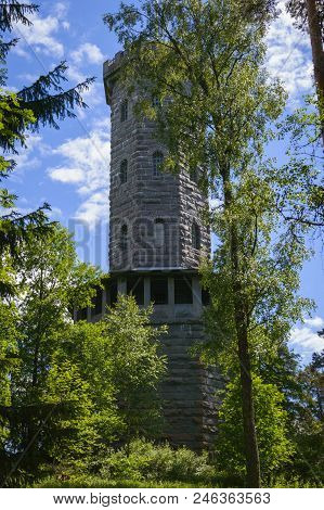 A Big And Old Tower Is Behind The Trees