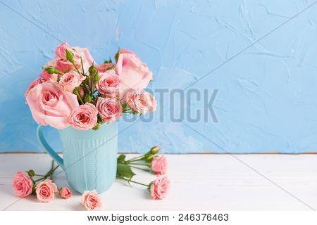 Background With Pnk Roses Flowers In Blue Cup Against  Blue Textured Wall. Floral Still Life.  Selec