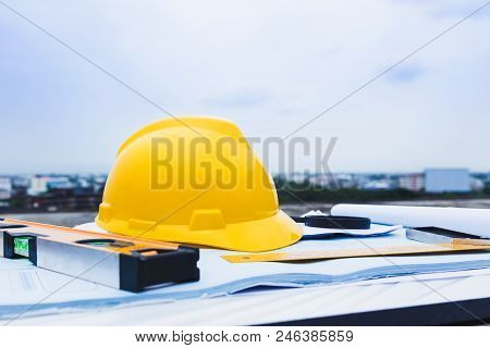 Engineer Constrction Safety Helmet And Other Tools On Top Of Building Blueprint Outside At Construct