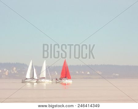 Three Sailboats In The Distance On The Horizon In A Quiet, Windless Weather. Two White Sailboats And
