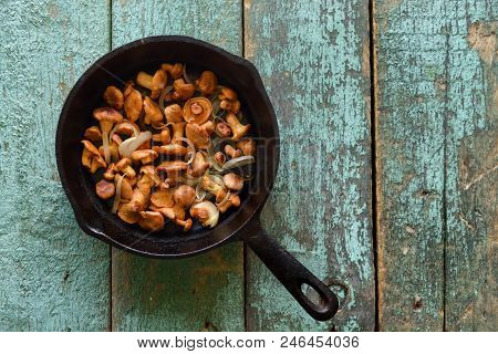 Wild Edible Mushrooms. Chanterelle Mushrooms Fried In Cast Iron Pan With Onion On Shabby Blue Backgr