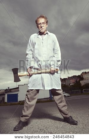 Older Paramedic Freak Man In Medical Coat And Protective Helmet Threating With Double Axe