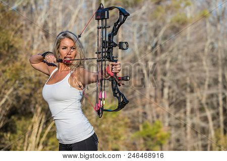 A beautiful blonde model posing with a bow and arrow outdoors