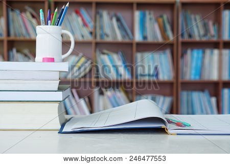 Pencil, Book And Notebooks On The Library Desk For Reading.