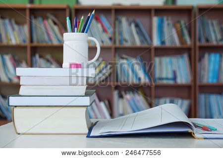 Pencil, books and notebooks on the library desk for reading.