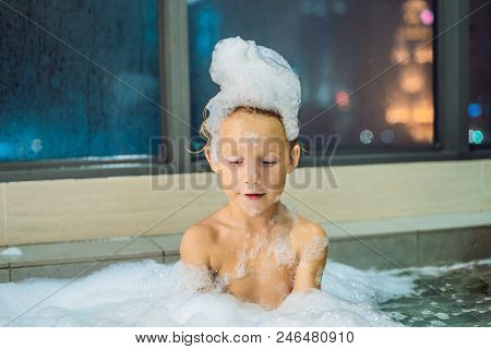 Happy Little Baby Boy Sitting In Bath Tub In The Evening Before Going To Sleep On The Background Of 