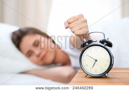 Sleepy Young Woman Stretching Hand To Ringing Alarm Willing Turn It Off. Early Wake Up, Not Getting 