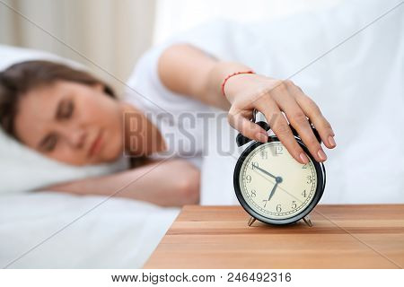 Sleepy Young Woman Stretching Hand To Ringing Alarm Willing Turn It Off. Early Wake Up, Not Getting 