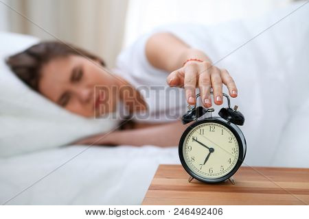 Sleepy Young Woman Stretching Hand To Ringing Alarm Willing Turn It Off. Early Wake Up, Not Getting 