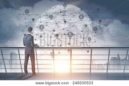 Young Businessman With A Beard Wearing A Gray Suit Is Standing And Holding Papers. Bitcoin Network H