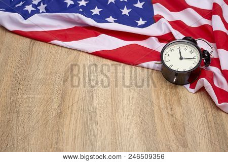 National flag of America and black alarm clock on old wooden background