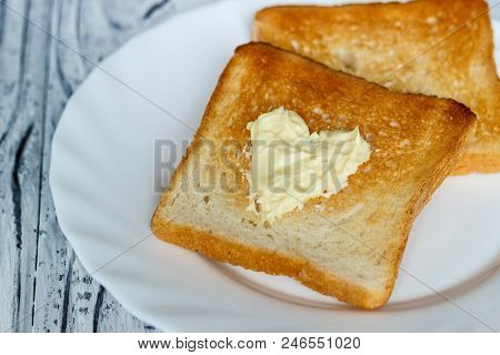 Still Life With Bread And Butter In A White Plate On A Wooden Background