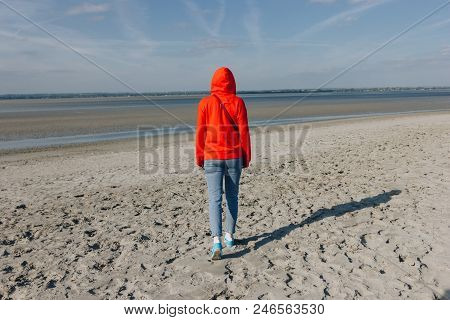 Back View Of Girl In Red Hoodie Walking On Beach, Saint Michaels Mount, France
