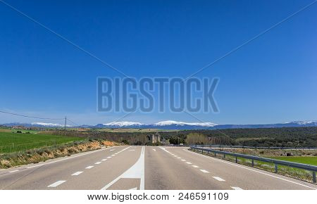 Highway Leading To A Snowcapped Mountain Range In Castilla Y Leon, Spain