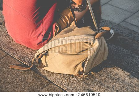 Back View Of The Young Traveller In Marsala T-shirt Holding Brown Canvas Bacpack. Concept Of The Cit