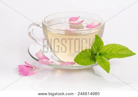 Glass Cup Of Tea With Mint Leaves And Rose Petals On Light Table