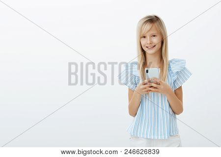 Little Kid Stole Dads Cellphone To Play Games. Portrait Of Charming Happy Young Girl With Blond Hair