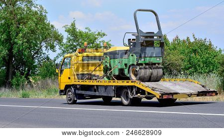 Tow Truck And Asphalt Paver On The City Road