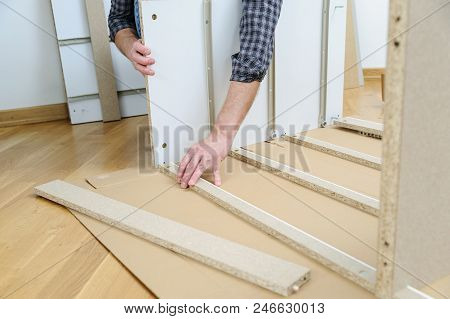 A Man Is Assembling Furniture From Chipboard Boards.