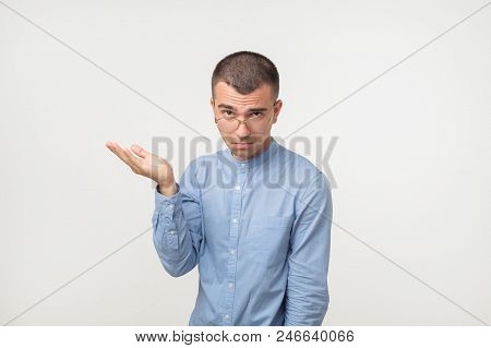 Young Man In Blue Shirt Standing Disorientated Bewildered Isolated On Gray Wall Background. Decision