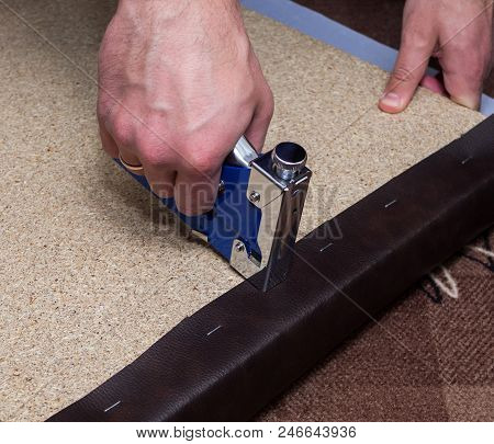 Upholsterer Covering Paricle Board With Brown Leather Using Stapler In The Atelier