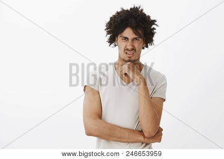 Indoor Shot Of Unimpressed Attractive Gay Model With Tanned Skin And Afro Haircut, Wrinkling Nose An
