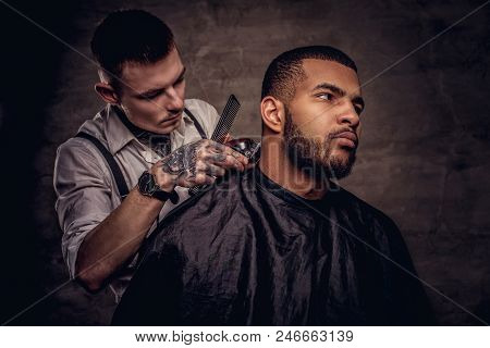 Old-fashioned Professional Tattooed Hairdresser Does A Haircut To An African American Client, Using 