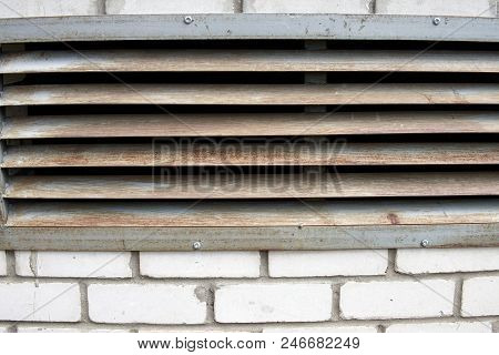 A Brick Wall With A Rusty Iron Grille In It