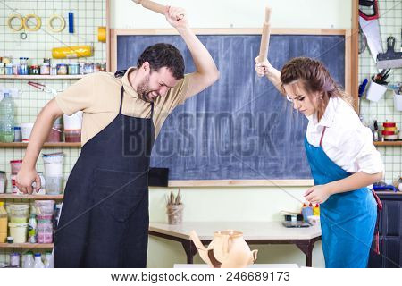 Two Caucasian Ceramists Squarrel And Crashing Clay Bowl On Table In Front With Rolling Pins. Negativ