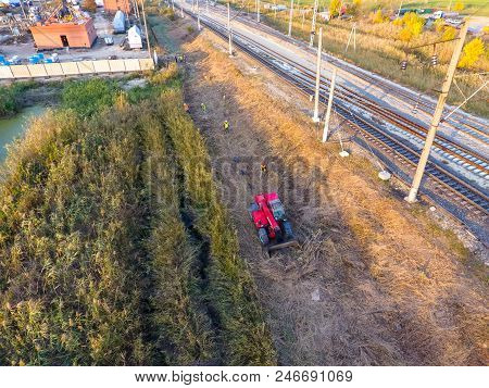 The Bulldozer Clears The Space Along The Railway Tracks. Raking Of Reeds By Bulldozer.