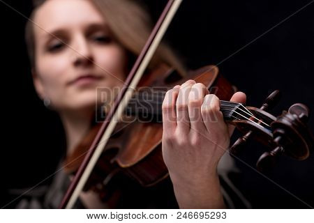 Young Woman With Half Of Her Hair Shaved While Playing A Baroque Violin On A Black Background