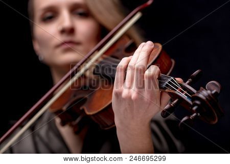 Young Woman With Half Of Her Hair Shaved While Playing A Baroque Violin On A Black Background