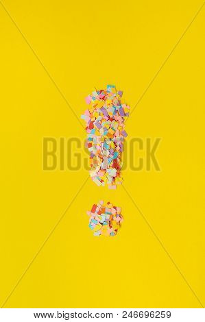 Multi-colored Confetti From Paper. The Exclamation Mark On A Yellow Background From Multi-colored Co