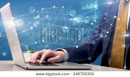 Businessman typing on laptop with linked reports charts grapghs around