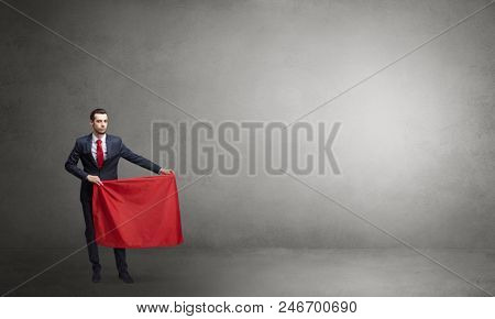 Businessman standing with red toreador cloth in his hand in an empty room