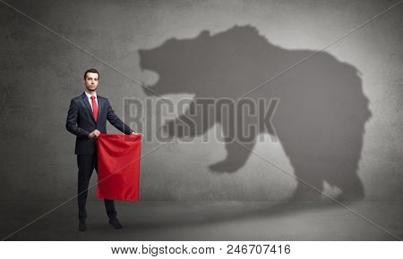 Businessman standing with red cloth in his hand and big bear shadow on his background