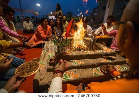 VARANASI, INDIA - MAR 22, 2018: People sit near a ceremonial fire near the Holy Ganges at night. Manikarnika Ghat is one of the ghats in Varanasi and is most known for being a place of Hindu cremation