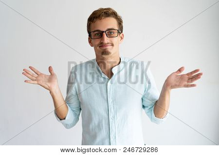 Smiling Careless Blonde Guy Showing Do Not Know Gesture. Young Caucasian Man In Glasses Throwing Up 