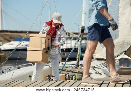 Senior yachtsman with packed carton boxes preparing for sea trip on his yacht