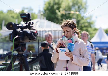 ST. PETERSBURG, RUSSIA - JUNE 20, 2018: Journalist of France 24 prepares to reportage at FIFA Fan Fest in Saint Petersburg during FIFA World Cup Russia 2018. The city hosts 7 matches of FIFA World Cup
