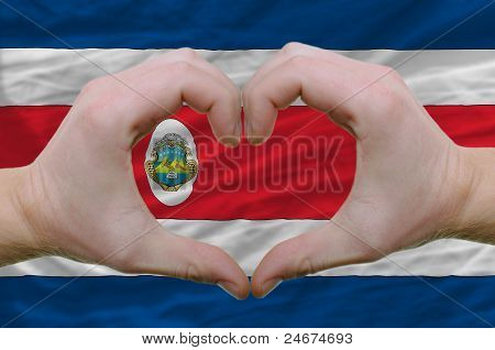 Cuore e gesto di amore ha mostrato le mani sopra la bandiera della Costa Rica sfondo
