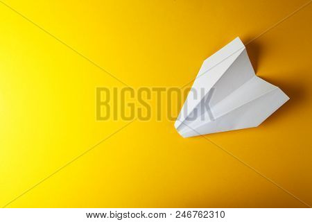 Paper Airplane On A Bright Yellow Background. Studio Shot