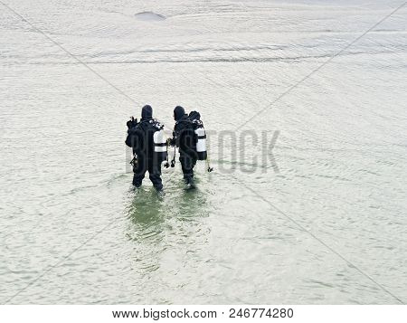 Prerow Germany - January 25 2018: Two Winter Scuba Divers Walking With Their Gear In Shallow Water T