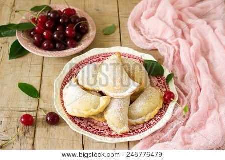 Pies With Cherries, Sprinkled With Powdered Sugar And Berries Of Fresh Cherries On A Wooden Surface.