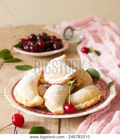 Pies With Cherries, Sprinkled With Powdered Sugar And Berries Of Fresh Cherries On A Wooden Surface.