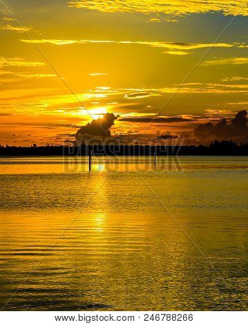 The golden morning sun breaking over a dark cloud on the Indian River Lagoon in Martin County, Florida