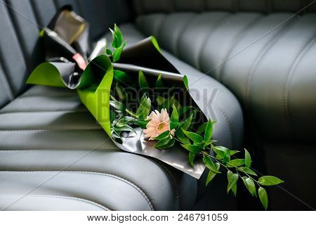 Handmade Creative Bouquet With Gerbera Flower Wrapped In Craft Paper On Dark Leather Sofa, Selective