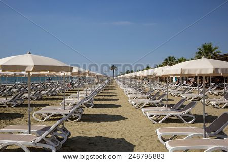 Mackenzie sandy beach at Larnaca, Cyprus. Sun loungers and umbrellas next to sea. Blue sky backdrop, closeup view.