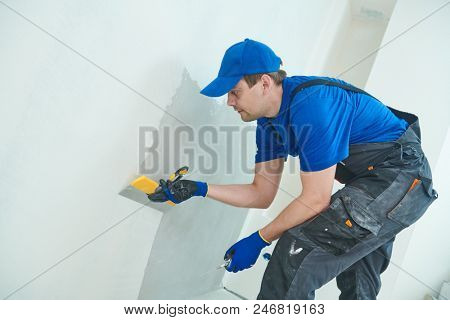 refurbishment. Worker spackling a wall with putty